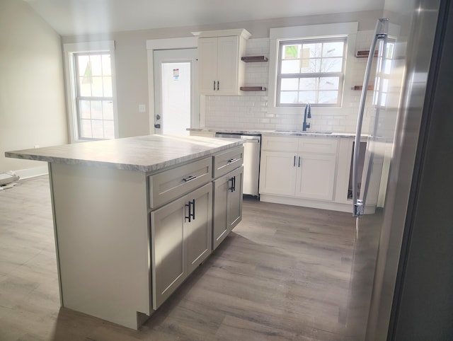 kitchen with a kitchen island, appliances with stainless steel finishes, tasteful backsplash, white cabinetry, and sink