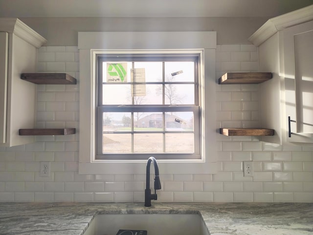 kitchen with sink, decorative backsplash, and light stone countertops