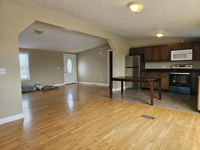 kitchen featuring light hardwood / wood-style floors, a textured ceiling, and appliances with stainless steel finishes