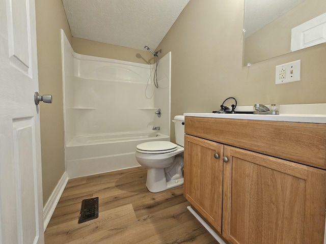 full bathroom featuring vanity, hardwood / wood-style flooring, toilet, a textured ceiling, and shower / bath combination