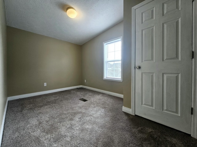 carpeted spare room featuring a textured ceiling and vaulted ceiling