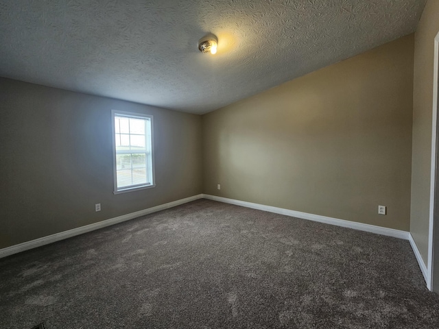 empty room with dark colored carpet and a textured ceiling