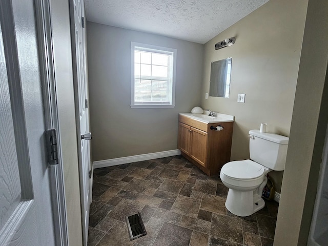 bathroom featuring vanity, toilet, and a textured ceiling