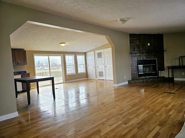 unfurnished living room featuring a fireplace, light wood-type flooring, and a textured ceiling