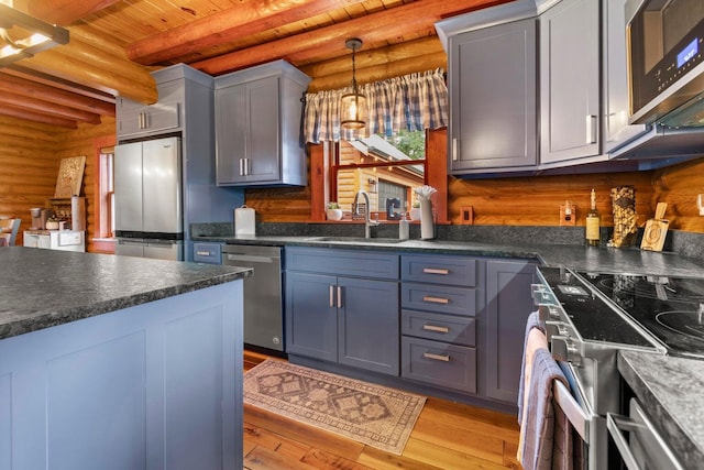 kitchen featuring light hardwood / wood-style flooring, sink, rustic walls, and stainless steel appliances