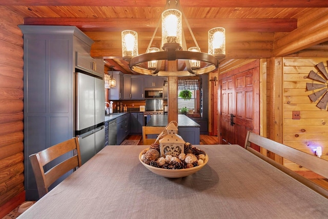 dining room featuring beamed ceiling, a chandelier, rustic walls, and dark wood-type flooring