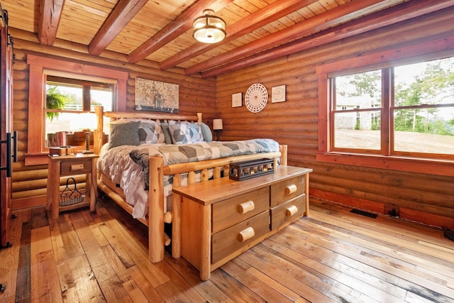 bedroom with beam ceiling, light hardwood / wood-style floors, rustic walls, and wood ceiling