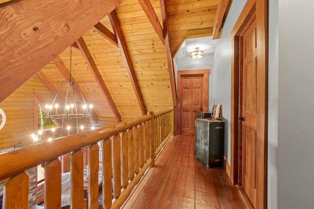 hallway featuring wood walls, lofted ceiling with beams, a notable chandelier, wood-type flooring, and wood ceiling