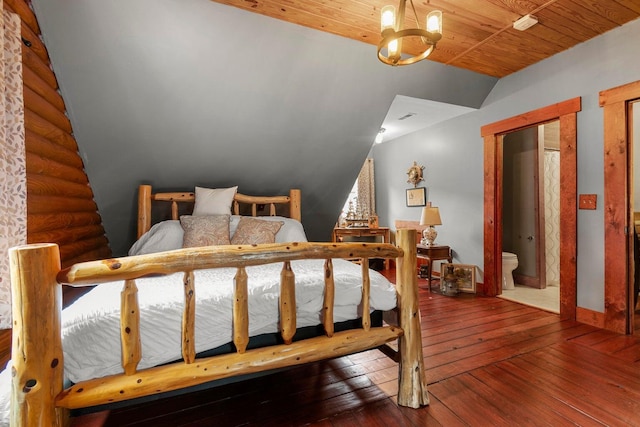 bedroom with ensuite bathroom, dark hardwood / wood-style flooring, lofted ceiling, and an inviting chandelier