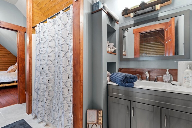 bathroom with wood-type flooring, vanity, and lofted ceiling