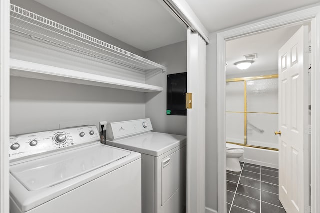 laundry area with washing machine and dryer and dark tile patterned floors