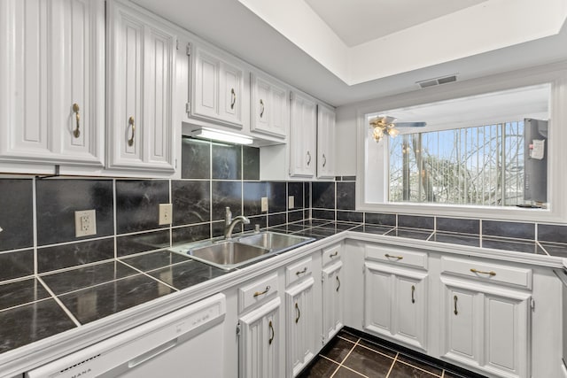 kitchen featuring sink, white cabinets, dishwasher, dark tile patterned floors, and backsplash