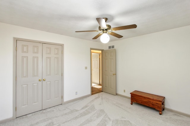 unfurnished bedroom with light carpet, a closet, and ceiling fan