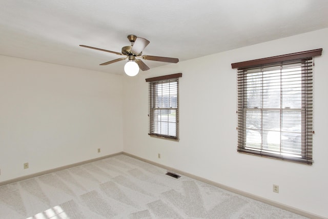 carpeted spare room featuring ceiling fan and a healthy amount of sunlight