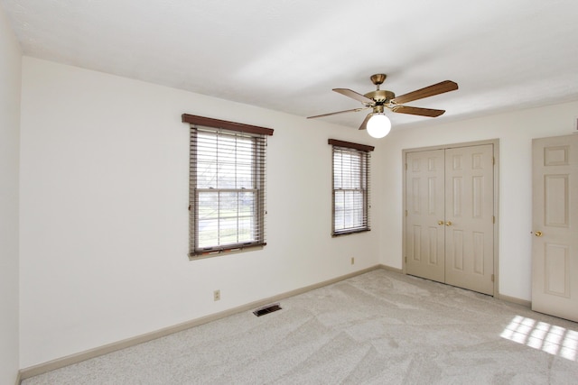 unfurnished bedroom with ceiling fan, a closet, and light colored carpet