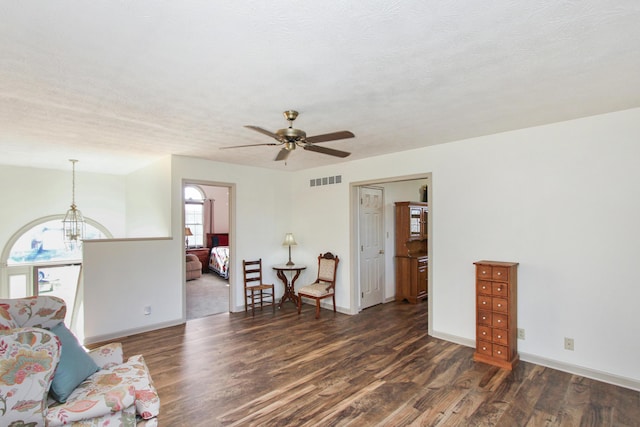 interior space featuring ceiling fan with notable chandelier, dark hardwood / wood-style flooring, and a textured ceiling