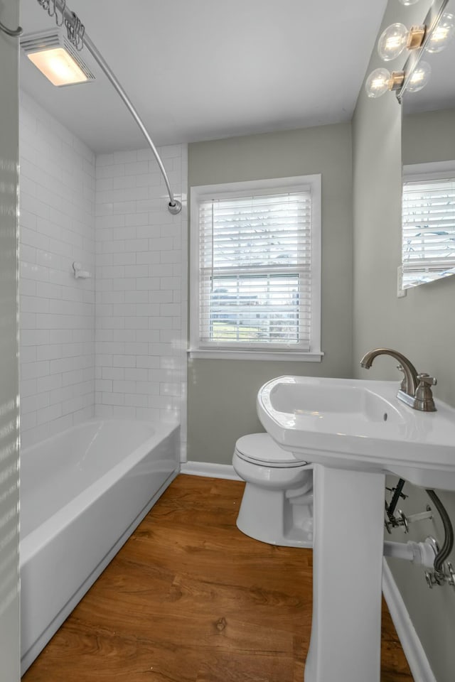 bathroom with toilet, tiled shower / bath combo, and hardwood / wood-style flooring