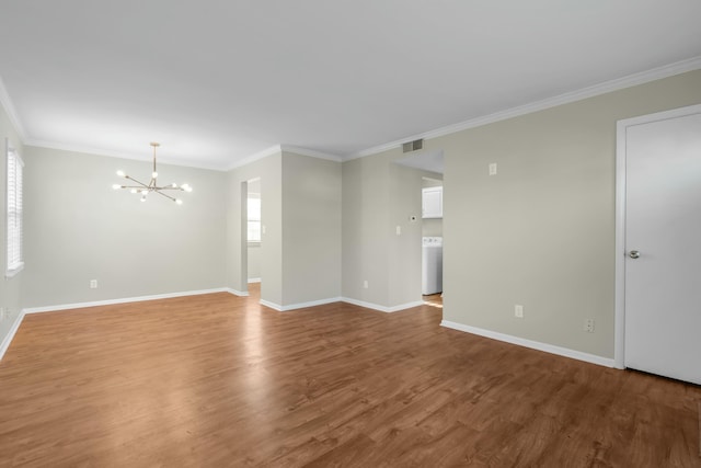 unfurnished room featuring hardwood / wood-style floors, washer / clothes dryer, an inviting chandelier, and ornamental molding