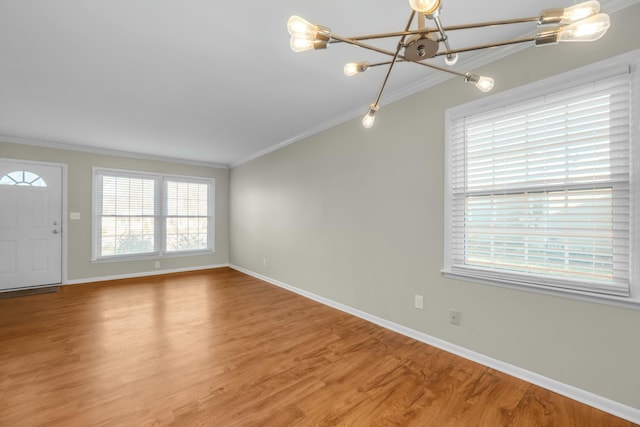 unfurnished living room featuring wood-type flooring, ornamental molding, and an inviting chandelier