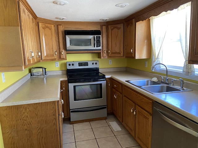 kitchen featuring sink, light tile patterned floors, stainless steel appliances, and a textured ceiling