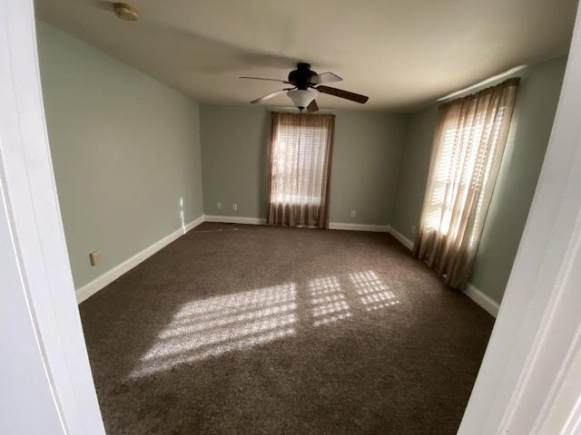 spare room featuring ceiling fan and dark colored carpet