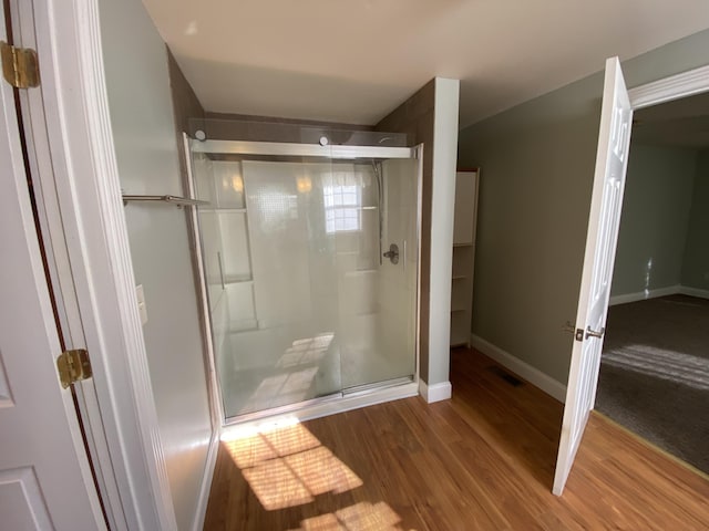 bathroom with an enclosed shower and wood-type flooring