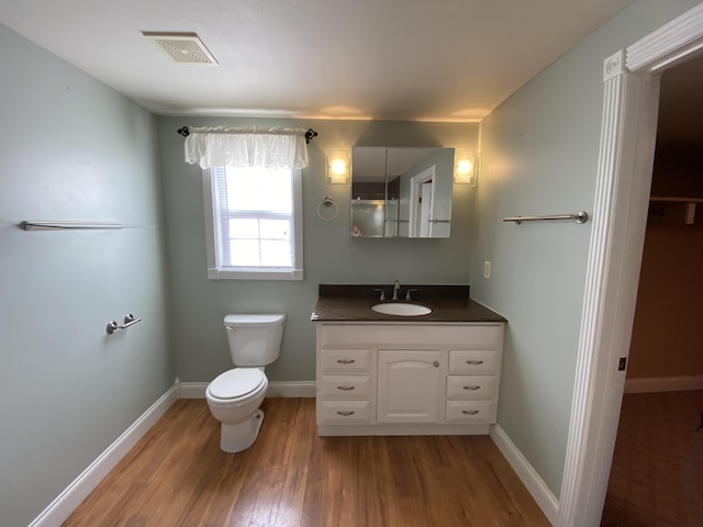 bathroom with toilet, vanity, and hardwood / wood-style flooring