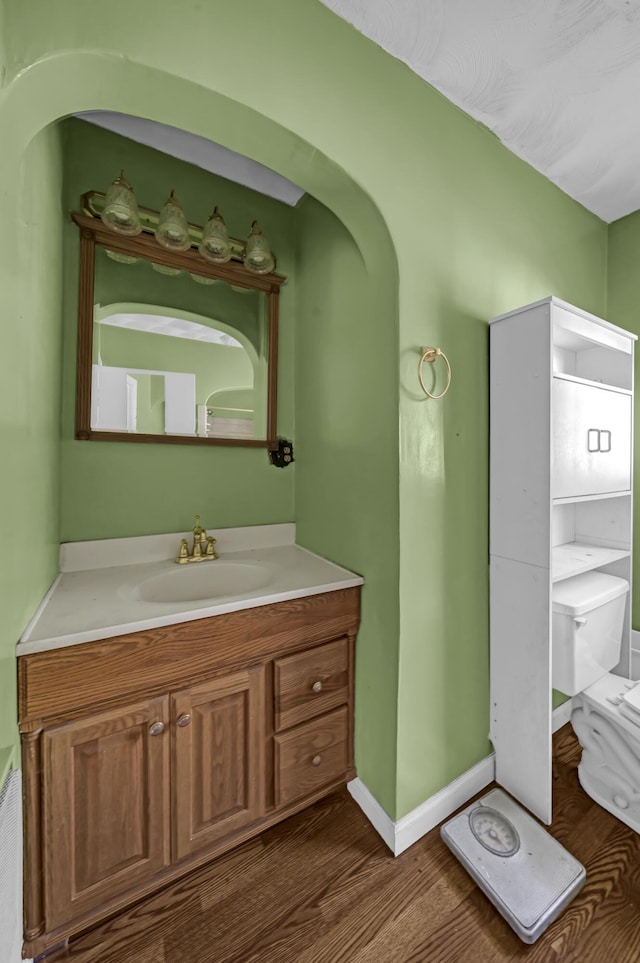 bathroom with toilet, vanity, and hardwood / wood-style flooring