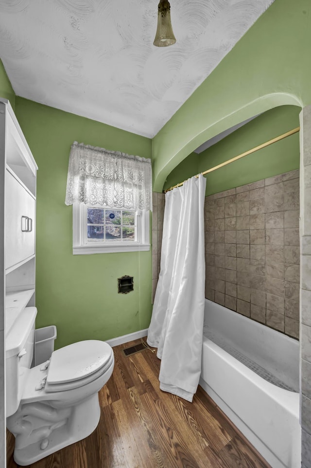 bathroom with hardwood / wood-style floors, shower / bath combo, and toilet