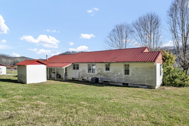 rear view of house with a lawn, central AC, and a storage unit