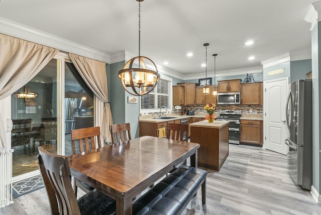 dining space featuring light hardwood / wood-style flooring, an inviting chandelier, crown molding, and sink