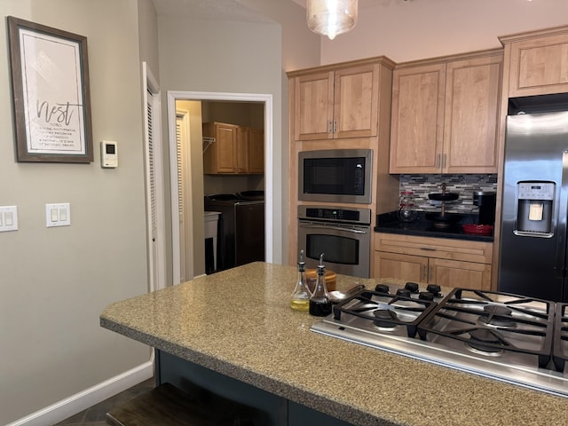 kitchen with tasteful backsplash, washing machine and dryer, a breakfast bar, and stainless steel appliances