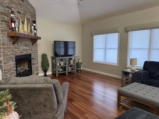 living room with a stone fireplace, lofted ceiling, and dark wood-type flooring