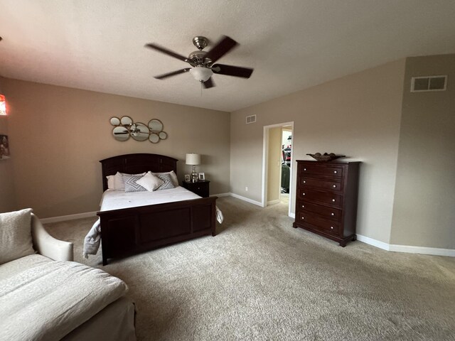 bedroom featuring a walk in closet, ceiling fan, a closet, and light carpet