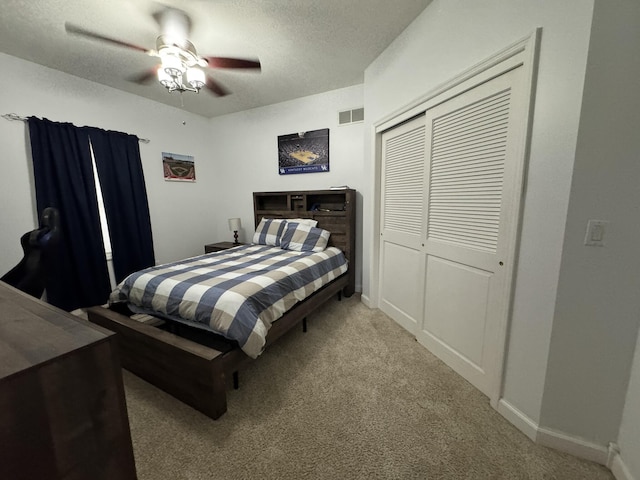 carpeted bedroom with a textured ceiling, a closet, and ceiling fan