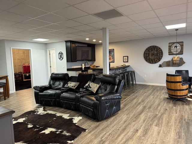 living room with hardwood / wood-style floors, a paneled ceiling, and wet bar