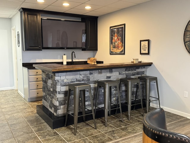 bar featuring a drop ceiling, dark hardwood / wood-style flooring, and sink