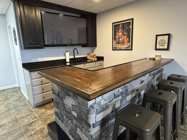 bar with tile patterned flooring, a drop ceiling, and sink