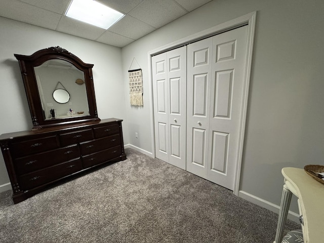 carpeted bedroom featuring a closet and a drop ceiling