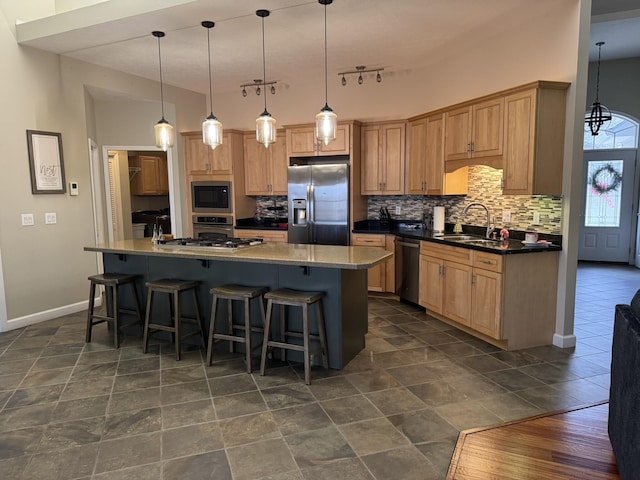 kitchen featuring a breakfast bar, sink, an island with sink, decorative light fixtures, and stainless steel appliances