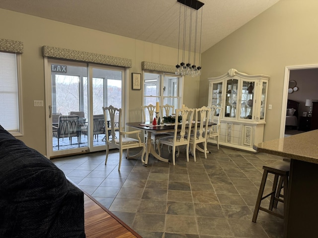 tiled dining area featuring a textured ceiling and vaulted ceiling