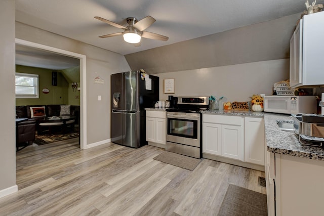 kitchen with light stone countertops, light wood-type flooring, stainless steel appliances, vaulted ceiling, and white cabinets