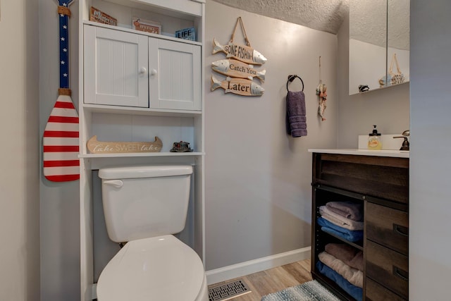 bathroom featuring vanity, toilet, wood-type flooring, and a textured ceiling