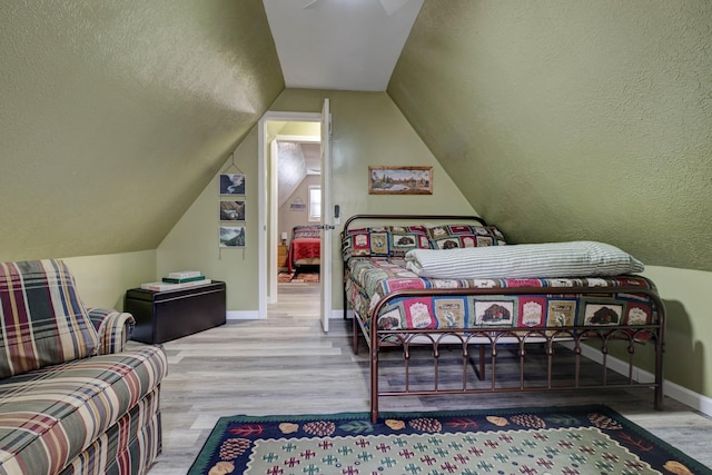 bedroom featuring lofted ceiling and light wood-type flooring