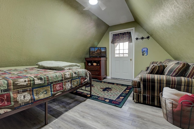 bedroom featuring a textured ceiling, light hardwood / wood-style floors, ceiling fan, and lofted ceiling