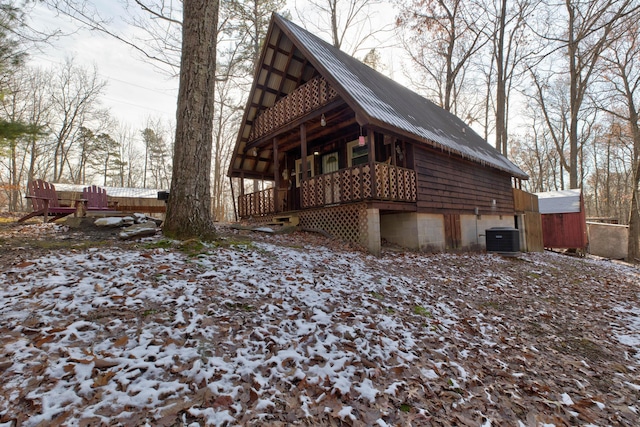 snow covered property featuring central AC and a storage unit