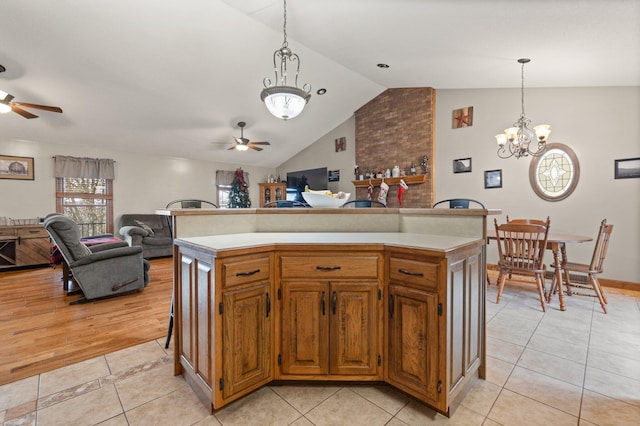 kitchen featuring ceiling fan with notable chandelier, a center island, vaulted ceiling, and hanging light fixtures