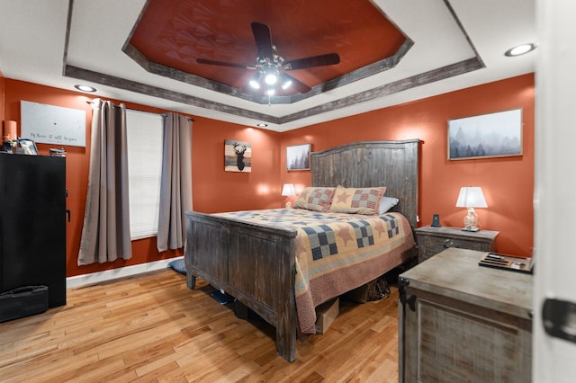 bedroom featuring a tray ceiling, ceiling fan, and light hardwood / wood-style flooring