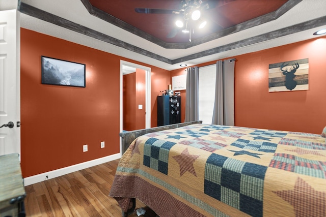 bedroom featuring wood-type flooring, a tray ceiling, and ceiling fan