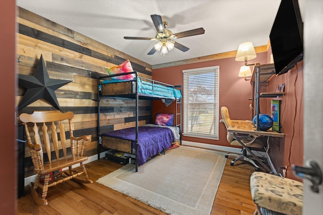 bedroom featuring wood-type flooring, ceiling fan, and wooden walls